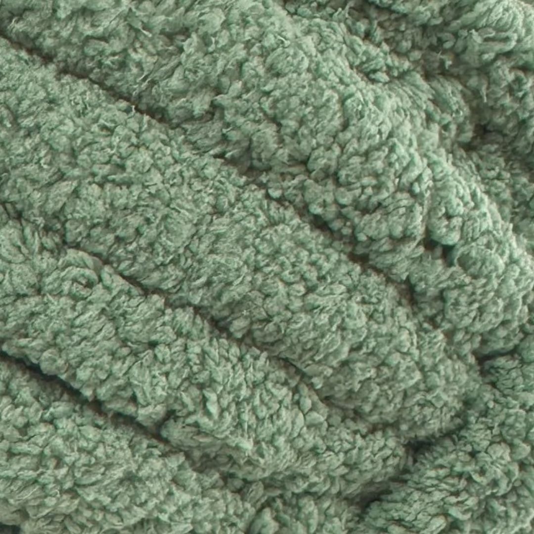 A close-up of a plush, textured polyester chenille yarn in a dusty sage green color.